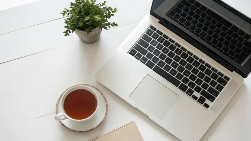 Laptop on clean desk with cup of tea